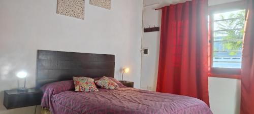 a bedroom with a bed with a red curtain and a window at CASA TEMPORADa 2027 DÚPLEX 2 HABITACIONES in Miramar