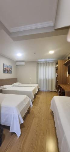 a room with a row of beds in it at Pousada Recanto do Mar in Navegantes