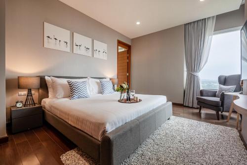 a bedroom with a large bed and a chair at White Sands Beachfront l 2BR Condo with Ocean View in Na Jomtien