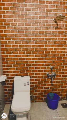 a bathroom with a toilet and a brick wall at The Haira Retreat in Kappil