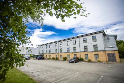 a large white building with cars parked in a parking lot at The Welcome Inn in Rotherham