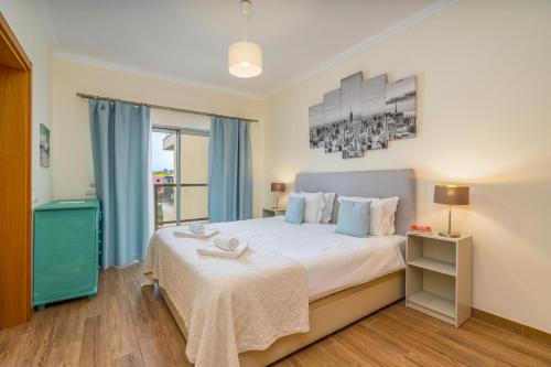 a bedroom with a large bed with blue curtains at #010 Marina View Apartment Pool & Balcony in Albufeira