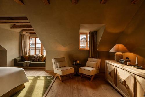 a bedroom with a bed and a couch and chairs at Castel Badia - The Leading Hotels of the World in San Lorenzo di Sebato