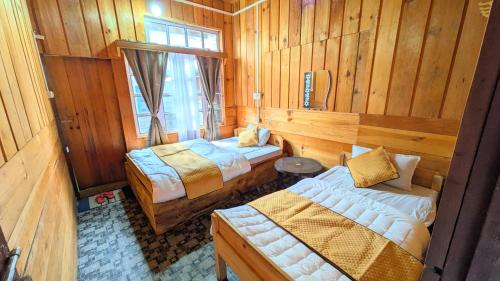 a room with two beds in a wooden cabin at Accomoon Valleyside homes in Mechuka