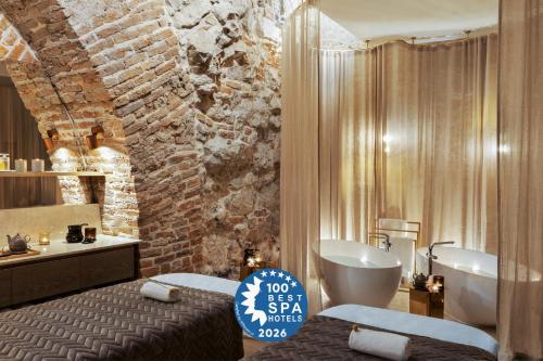 a bathroom with a brick wall and a tub and a sink at H15 Palace, a Luxury Collection Hotel, Krakow in Krakow