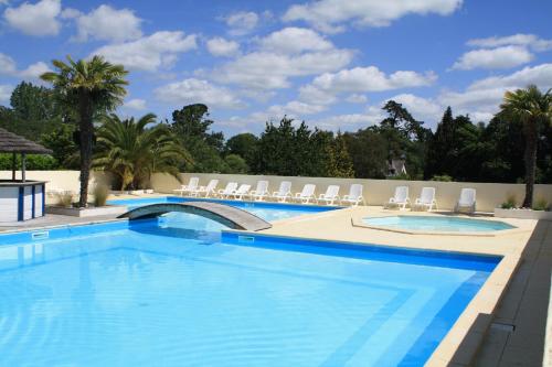 a large swimming pool with chairs and trees at Camping Kerscolper - Mobil home 3 pièces 4/6 personnes + TV MAE-9591 in Fouesnant