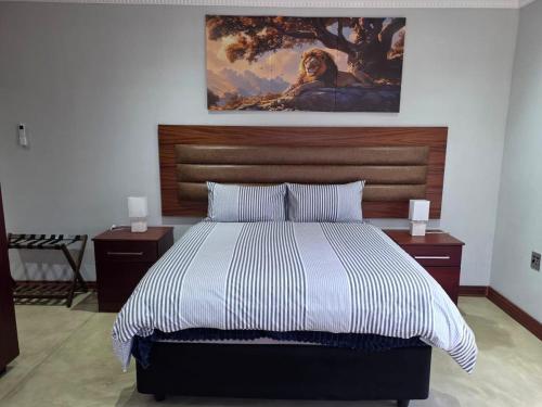 a bedroom with a bed with a painting on the wall at Bush Diamond Lodge in Cullinan