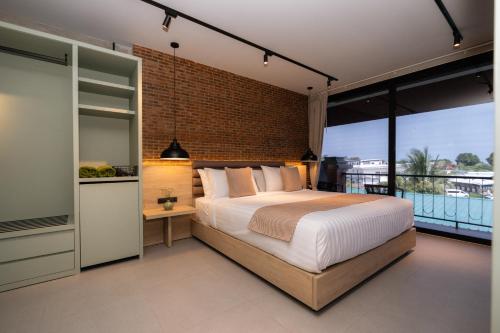a bedroom with a large bed and a brick wall at Aloha Tropicana Samui in Chaweng