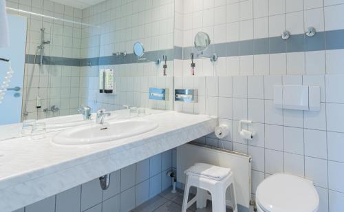 a bathroom with a sink and a toilet at Hotel Arkadia in Friedrichsdorf