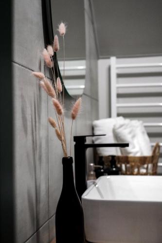a black vase with flowers in it next to a sink at Апартаменти Rest Hill in Vorokhta