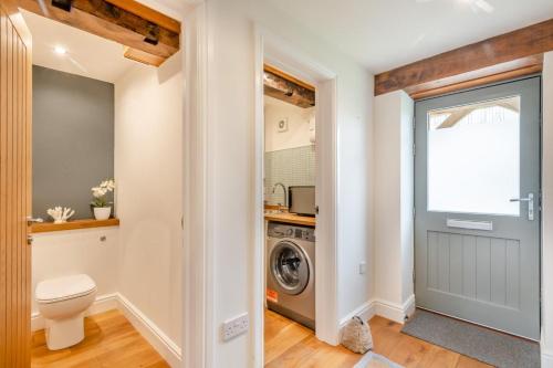 a bathroom with a toilet and a washer and dryer at 3 Bed in Little Snoring oc-m28145 in Little Snoring