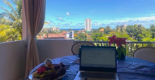 a laptop computer sitting on a table with a plate of fruit at BOUTIQUE-VILLA with Suites & Rooms in Karon Beach