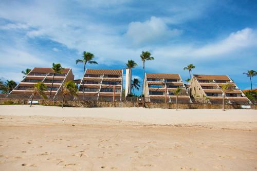 a row of condos on the beach with palm trees at Cumbuco Ocean View in Cumbuco