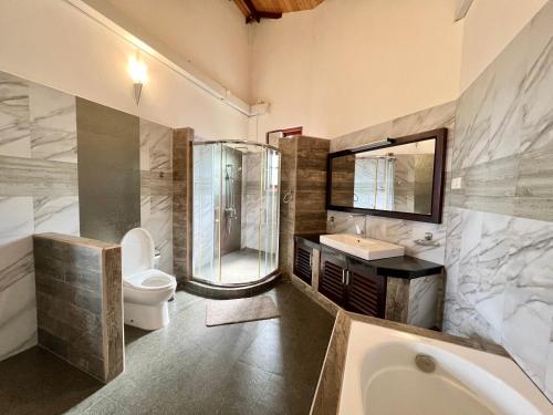 a bathroom with a shower and a toilet and a sink at The Grand Hanthana in Kandy
