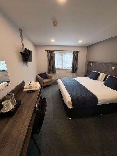 a hotel room with a large bed and a desk at Sandown Park Lodge in Esher