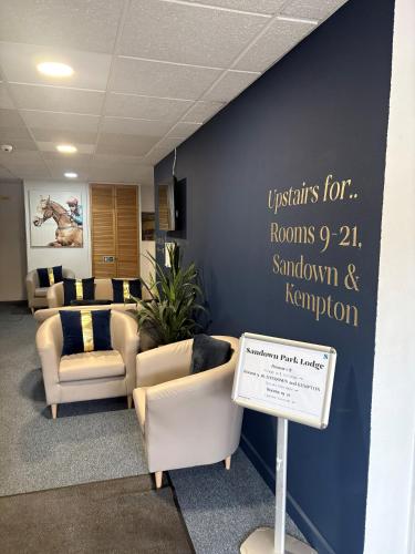 a waiting room with couches and a sign on a wall at Sandown Park Lodge in Esher