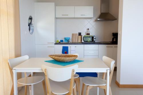 a white kitchen with a white table and chairs at Cantinho das Buganvilias AT**** in Queimada