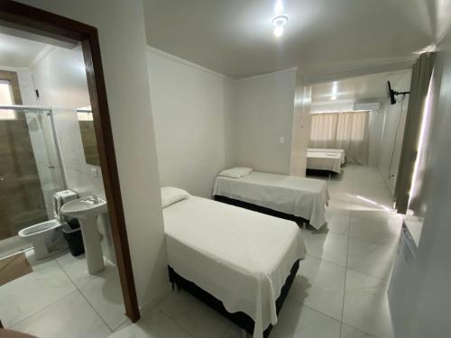 a hospital room with two beds and a bathroom at Hotel Acauã in Campo Mourão