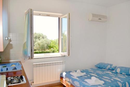 a bedroom with a bed and a window at Apartmani ANITA in Umag