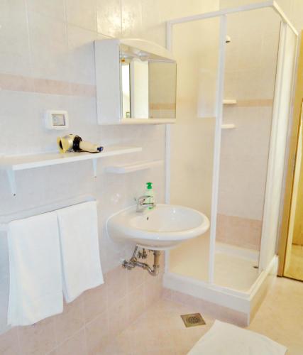 a white bathroom with a sink and a shower at Apartmani ANITA in Umag