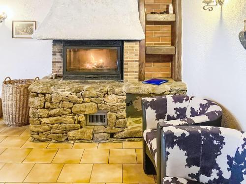 a stone fireplace in a living room with a chair at Apartment Les Grangettes by Interhome in Auberson
