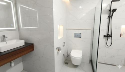 a white bathroom with a toilet and a shower at Hotel King Plaza in Nikurān