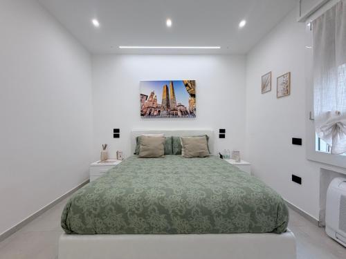 a white bedroom with a large bed with a green blanket at B&B Sabò in Bologna