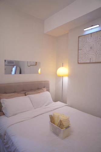 a white bed with a basket of towels on it at The Storeys - Mesaverte Residences CDO in Pontud