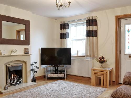 a living room with a flat screen tv and a fireplace at The Costins in Allonby