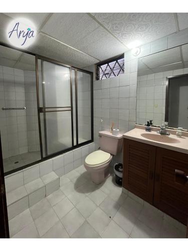 a bathroom with a toilet and a shower and a sink at Arya Land Yoga Hostel in Cali