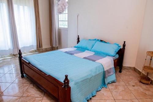 a bedroom with a bed with blue sheets and a window at Nazareth Guest House in Kigali