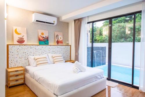 a bedroom with a bed and a large window at Tata pool villa pattaya in Jomtien Beach