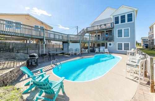 a swimming pool with chairs and a house at Paradise Found - Nags Head MP 16.5, Oceanfront, Ocean & Sound Views, Pool, Hot Tub, Pets OK in Nags Head