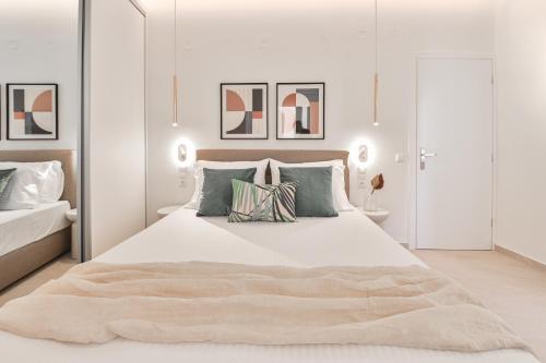 a white bedroom with a large bed with pillows at Elan Suites Preveza in Preveza