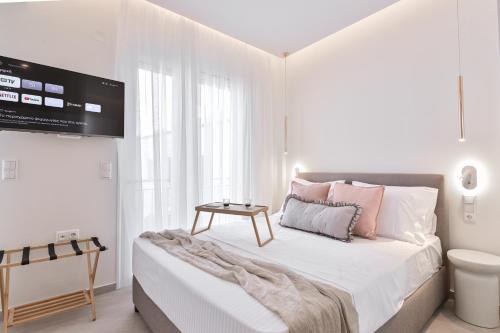 a white bedroom with a bed with a tv on the wall at Elan Suites Preveza in Preveza