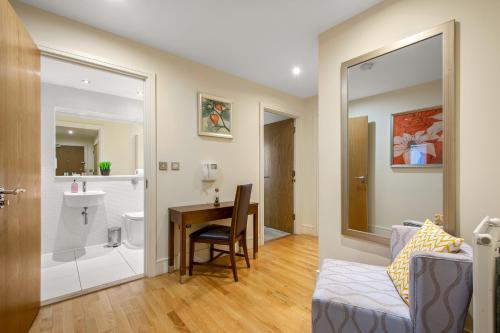 a living room with a table and a bathroom at MySquare Lanterns Way Apartments at Canary Wharf in London