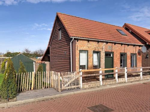a small brick house with a wooden fence at Holiday Home Helmrich by Interhome in Schoondijke