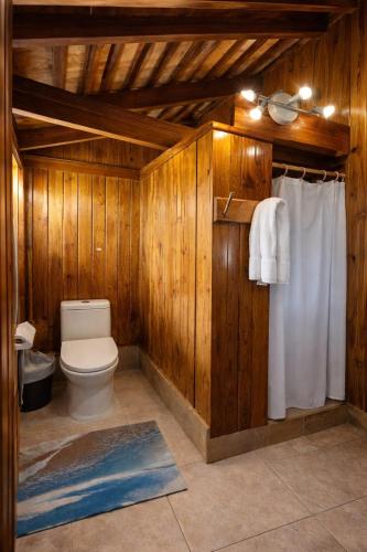 a bathroom with a toilet and wooden walls at Hotel Neptuno Refugio in Boca Chica