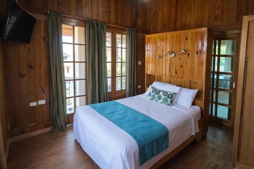 a bedroom with a bed with wooden walls and windows at Hotel Neptuno Refugio in Boca Chica