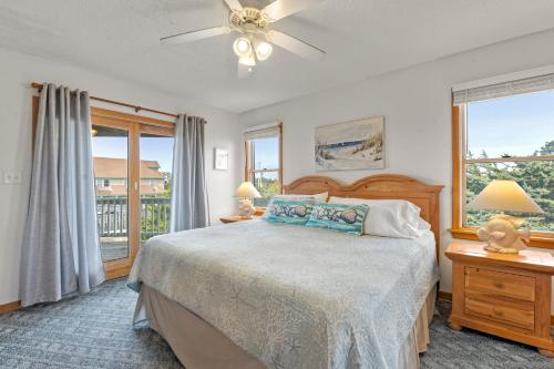 a bedroom with a bed with a ceiling fan and windows at Sea Spray in Waves