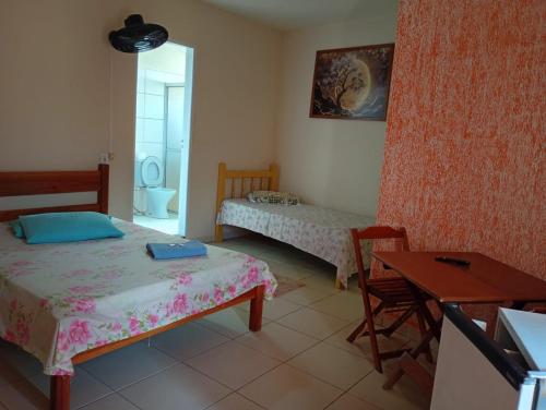 a room with two beds and a table and a desk at Pousada Real in Itamonte