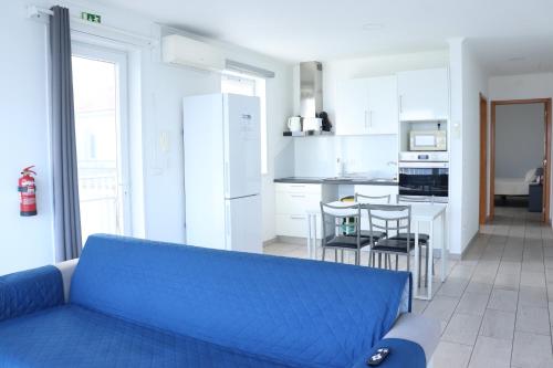 a living room with a blue couch in a kitchen at Faial Marina Apartments 2 in Horta