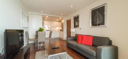 a living room with a gray couch and a red pillow at Talisman & Duckman Tower at Canary Wharf by MySquare in London