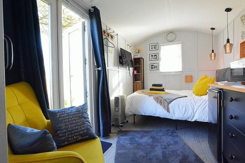 a bedroom with a bed and a yellow chair at Beautiful shepherd’s hut in Newmarket