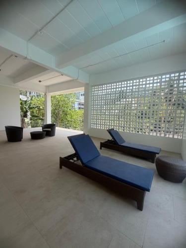 a large room with two blue chairs and windows at Apartment Karon SeaView 72 sq in Karon Beach