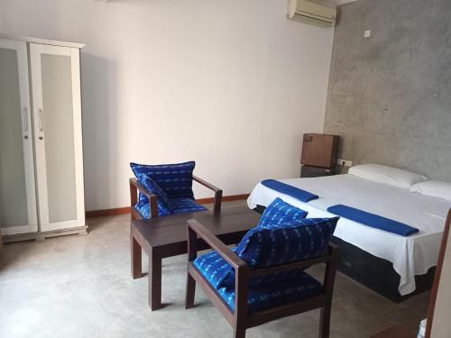 a bedroom with a bed and two chairs and a table at Blu EDGE BEACH RESORT in Katuneriya