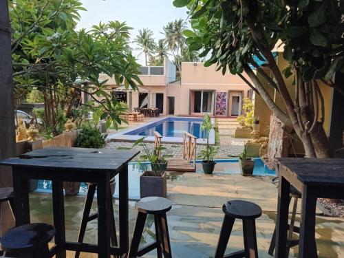 a patio with tables and stools in front of a pool at Blu EDGE BEACH RESORT in Katuneriya