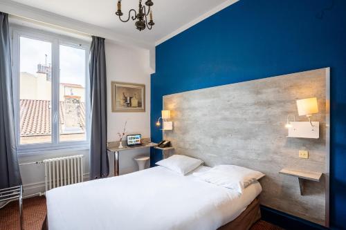 a bedroom with a white bed and a blue wall at Hôtel du Helder in Lyon