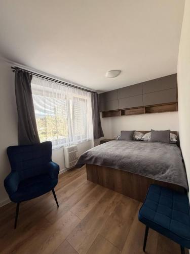 a bedroom with a bed and a chair and a window at Lipa Apartmán in Tlmače