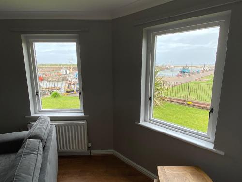 a living room with two windows and a couch at Ritson Wharf in Maryport